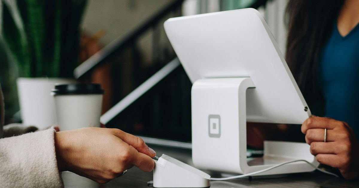 A customer paying by card at a tablet on a shop counter